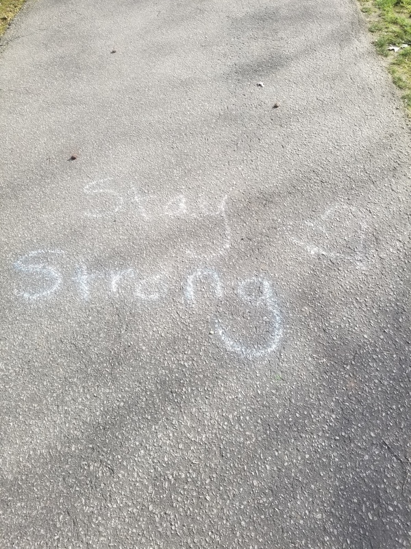 Chalk message on sidewalk saying Stay Strong.