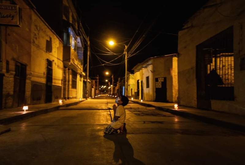 A little boy kneeling in the street at night. 