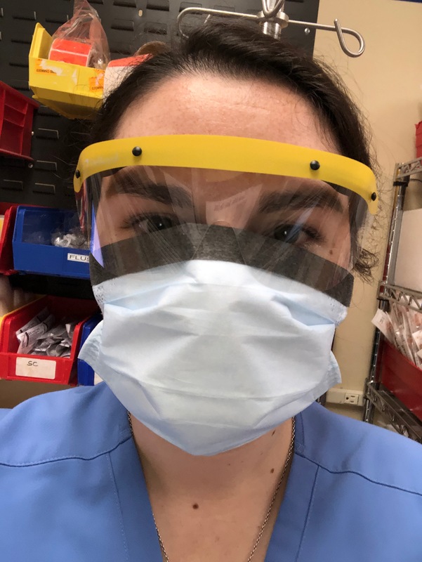 A nurse wearing a face mask and a clear eye covering.
