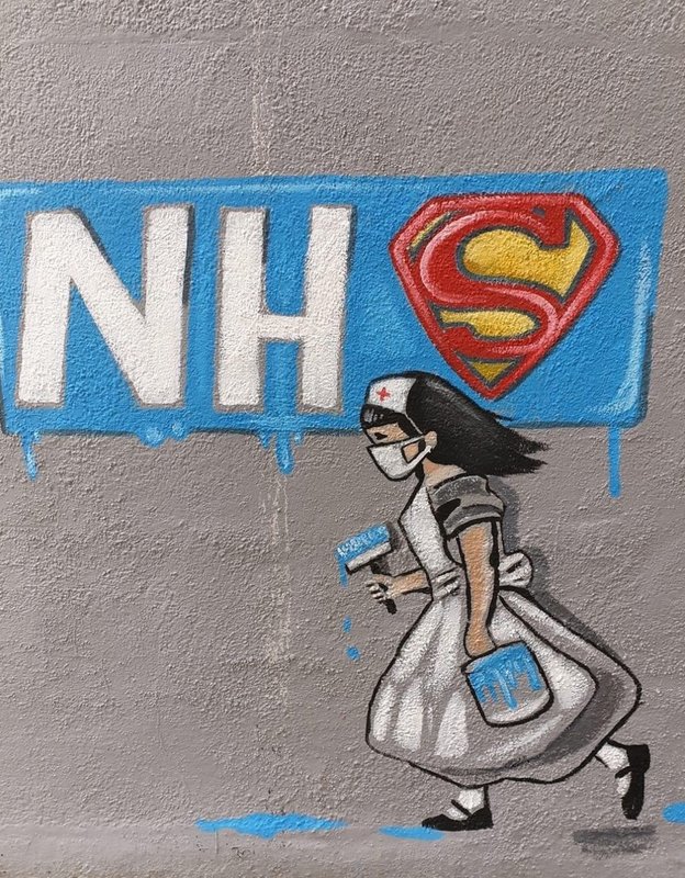 Graffiti on the side of a building of a nurse that painted NHS and the S is the Superman symbol. 