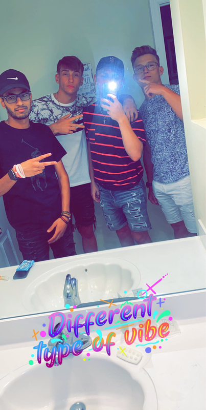 Four male college students posing in front of mirror with peace signs. 