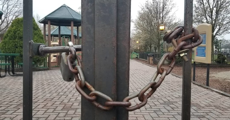 A gate that is locked surrounding a playground. 