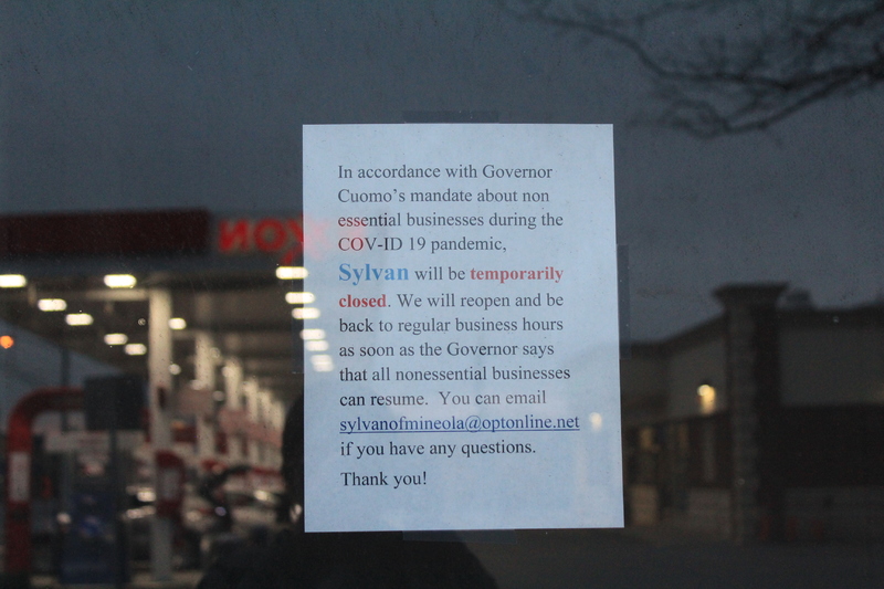 A window sign that say "In accordance with Governor Cuomo's mandate about nonessential businesses during the COV-ID19 pandemic, Sylvan will be temporarily closed. We will reopen and be back to regular business hours as soon as the Governor says that all nonessential businesses can resume. you can e-mail sylvanofmineola@optonline.net if you have any questions. Thank you!" 