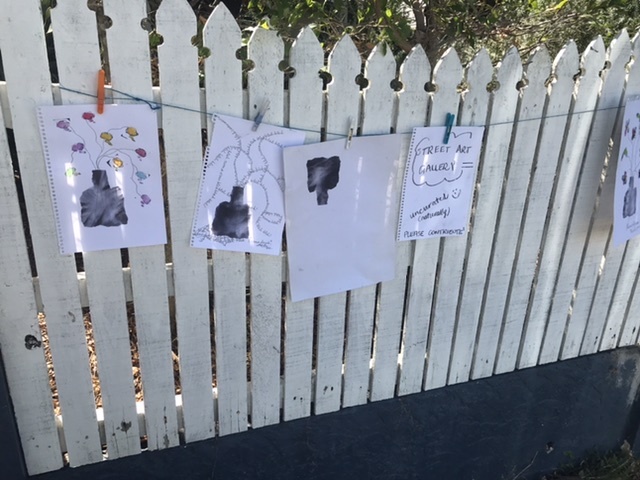 A fence with drawings hung on it. 