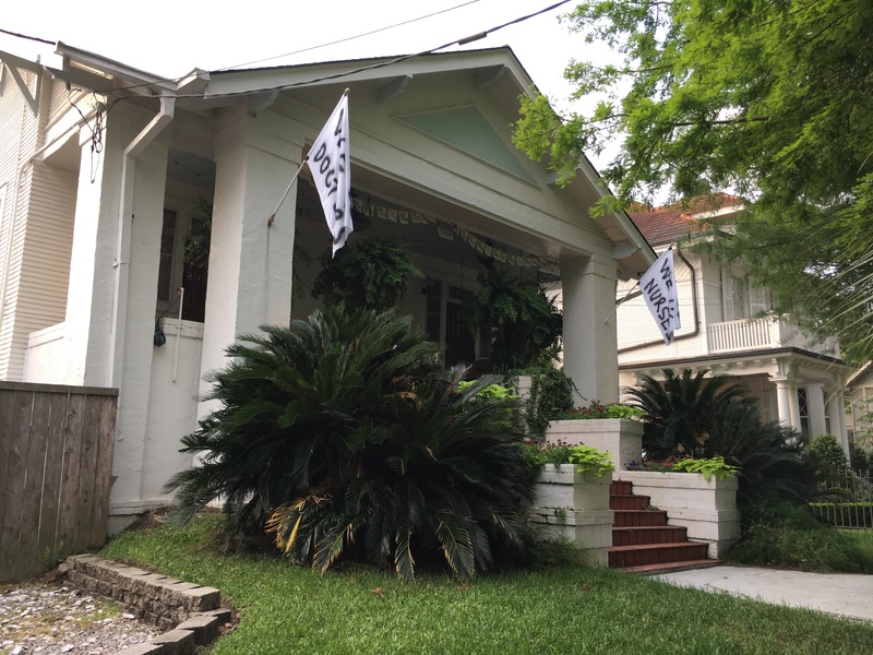 Two white flags hung on the front porch of a house that say "We (heart) doctors" and "We (heart) nurses."
