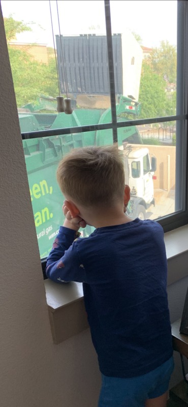 A child staring out of a window at a garbage truck. 