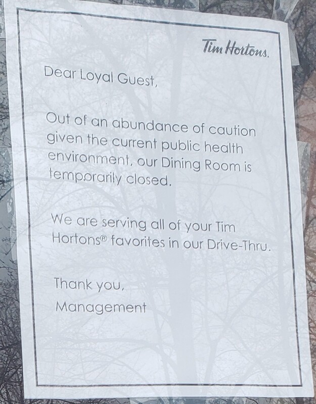 A sign at Tim Hortons reading "Dear Loyal Guest, Out of an abundance of caution given the current public health environment, our dining room is temporarily closed. We are serving all of your Tim Hortons favorites in our drive-thru. Thank you, management."