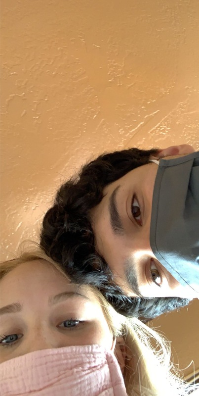 This is a picture taken of a boy and girl looking down at a camera while wearing face masks. 