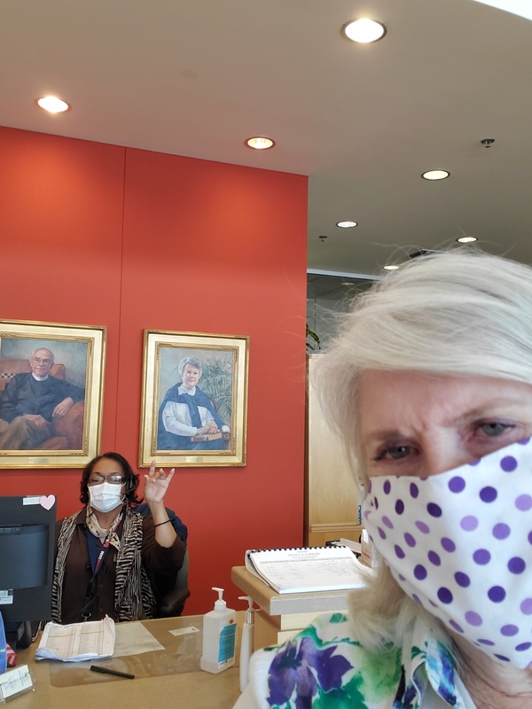 Two people with masks next to a desk. 