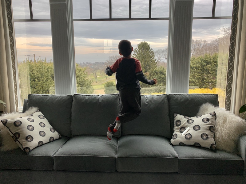 A kid looking through a window in a house. 