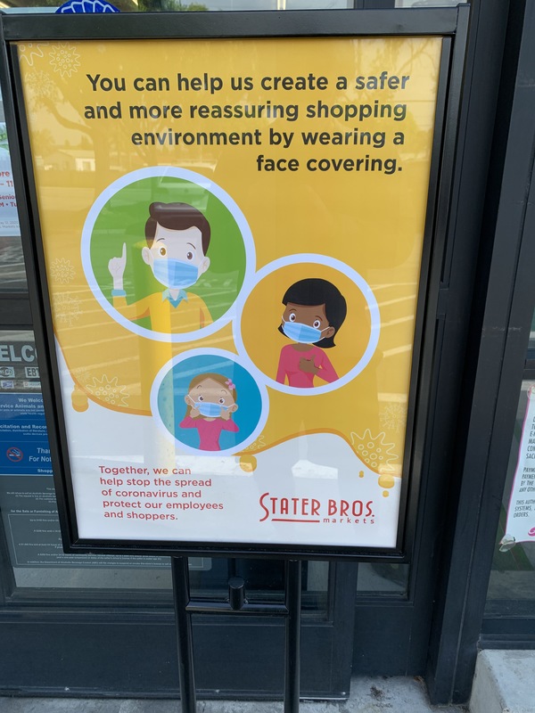 Image of a mall sign that says you can help us create a safer and more reassuring shopping environment by wearing a face covering.