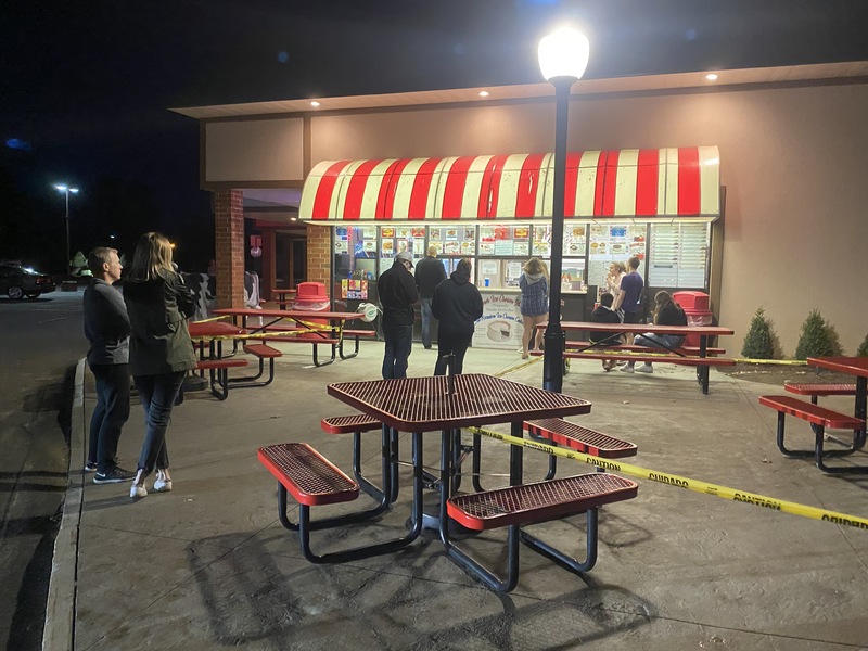 People waiting in line outside of an ice cream parlor.