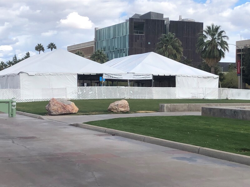 This is a picture of several white tents set up on a grassy area, most likely to provide vaccination shots. 