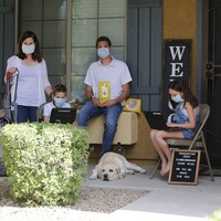 A family posing on their front porch wearing masks. 