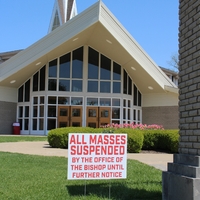 Church Yard Sign Reading "All Masses Suspended By The Office Of The Bishop Until Further Notice".