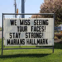 Sign reading "We miss seeing your faces! Stay Strong! Marians Hallmark".