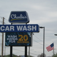 Blue sign for "Charlie's Car Wash" in Wichita, Kansas with white and yellow text saying, " WASH HANDS FOR 20 SECONDS." 