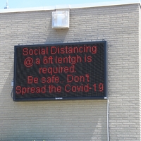 Digital Sign reading "Social Distancing at a 6 feet length is required. Be Safe. Don't spread COVID-19".