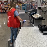 A person with a mask wiping down a register. 