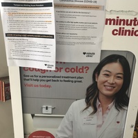 Information papers on a sign in CVS that talk about waiting room procedures due to COVID-19, CVS is currently not doing COVID-19 testing, and more information about COVID-19. 