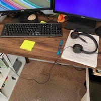 A desk sit up for remote work with two monitors, keyboard, and headset.