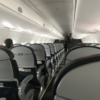 Inside of a flight cabin, there are only three people sitting in seats. 