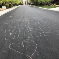 A street has chalk written on it that says: SPREAD GOOD VIBES.