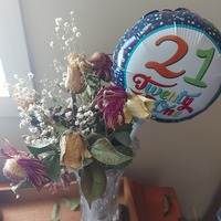 A picture of a balloon and a vase of flowers purchased for someone's 21st birthday. 