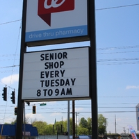 A sign outside a Walgreens reading "Senior Shop every Tuesday 8 to 9 AM".