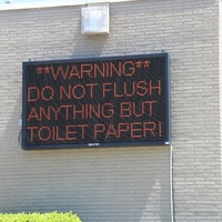 Digital Sign reading "Warning. Do not flush anything but toilet paper!"