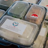Many to-go boxes of lunches with "Made with Love" sticker