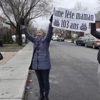 Three people with a sign reading "Bonne fete maman 103 ans".