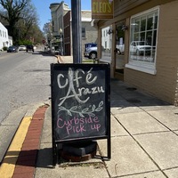 A chalkboard sign outside of a cafe reading "Curbside Pickup".