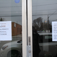 Two signs on entrance of a gym. 
First sign says: "If you are sick, please stay home! Otherwise... Lets work."
Second sign says: "Thanks to NY state and Gov Cuomo all gyms are closed until further notice. We appreciate your understanding and patience at this time. Stay calm and be safe."  
