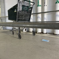 This is a picture of a face mask that has been discarded by a Whole Foods shopping cart in a parking garage. 