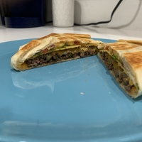 This is a picture taken of a type of grilled quesadilla, with cheese and meat inside. 