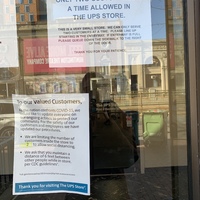 A piece of paper that is taped to the inside of a window informing customers about limiting how many people will be in their store and to practice social distancing. 