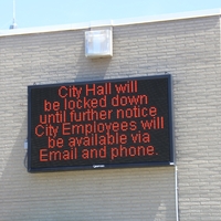 Digital sign reading "City hall will be locked down until further notice. City employees will be available via Email and Phone".