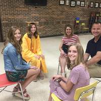 Image of a family sitting in a circle in chairs waiting for high school graduation to start. 