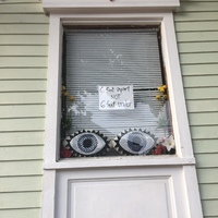 A residential window with a sign that says "6 feet apart nor 6 feet under."