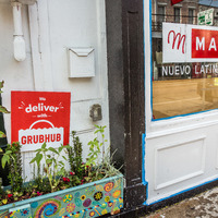 A "We deliver" Grubhub sign next to Mayas Nuevo Latino Cocina in New Orleans. 