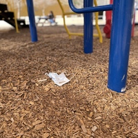 This is a picture of a lost face mask that was left on the ground in a playground. 