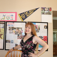 A woman standing in front of a wall decorated as a classroom background during distance learning.