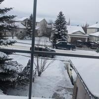 Photograph taken from inside of a window, looking out onto a snow-covered street.