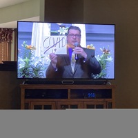 A TV screen featuring a man holding a sign with COVID-19 crossed out on it.