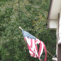 A shredded flag flying outside a house.