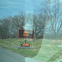 Image of a sign on the side of the highway which says stay home.