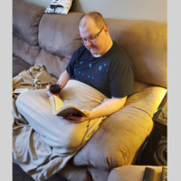 A photo of a man reading on a couch. 