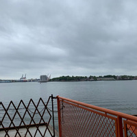 This is a picture taken from a pier, looking out onto a body of water with land visible on the other side.
