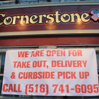 A restaurant called Cornerstone has a banner stating: "We are open for takeout, delivery, and curbside pickup" with their phone number underneath. 